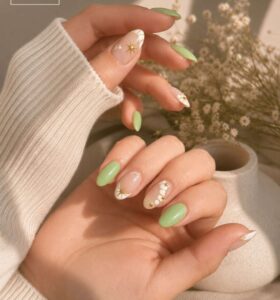 mint-green almond nails and white accent nails featuring a gold starburst and small gold beads.