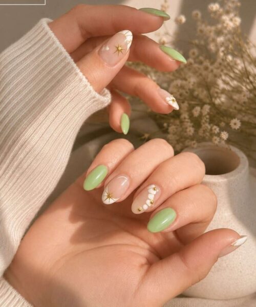 mint-green almond nails and white accent nails featuring a gold starburst and small gold beads.